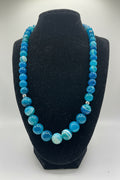 Blue beaded necklace on a black bust against a white background