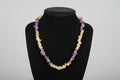 Black face mask with yellow and purple beads on a wooden surface