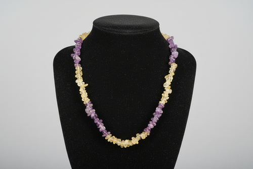 Black face mask with yellow and purple beads on a wooden surface