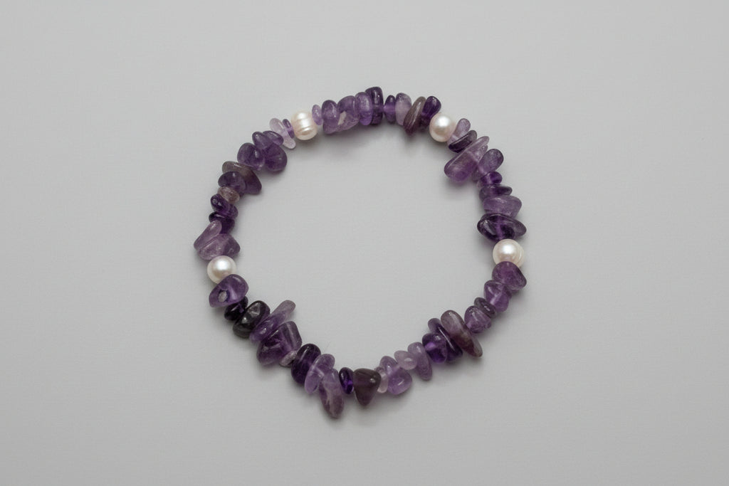 Amethyst and pearl bracelet on a wooden surface