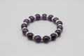 purple Amethyst beaded bracelet with silver accents on a wooden surface