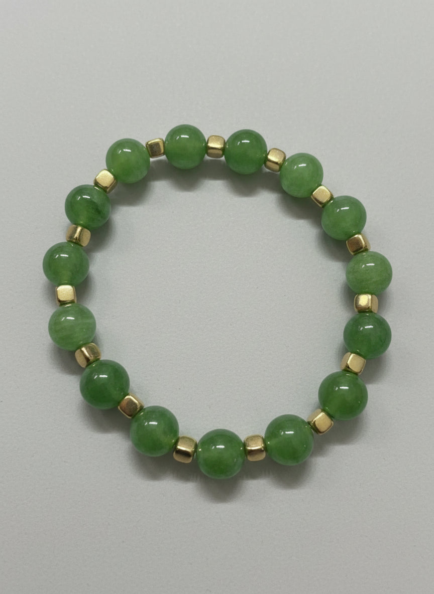 Green beaded bracelet with gold accents on a gray background