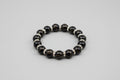 Black agate golden wire beaded bracelet with silver accents on a wooden surface