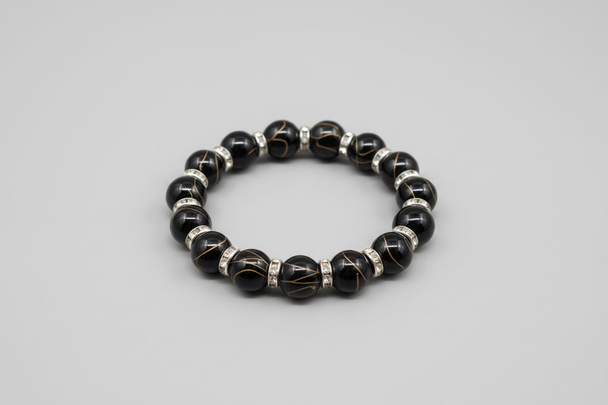 Black agate golden wire beaded bracelet with silver accents on a wooden surface