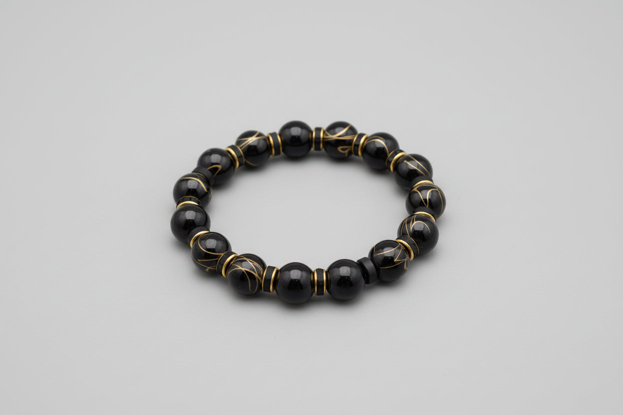 Black beaded bracelet with gold accents on a wooden surface