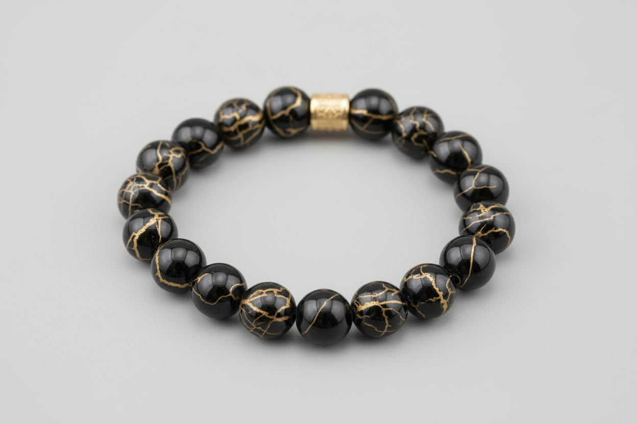 Black beaded bracelet with a gold accent on a wooden surface