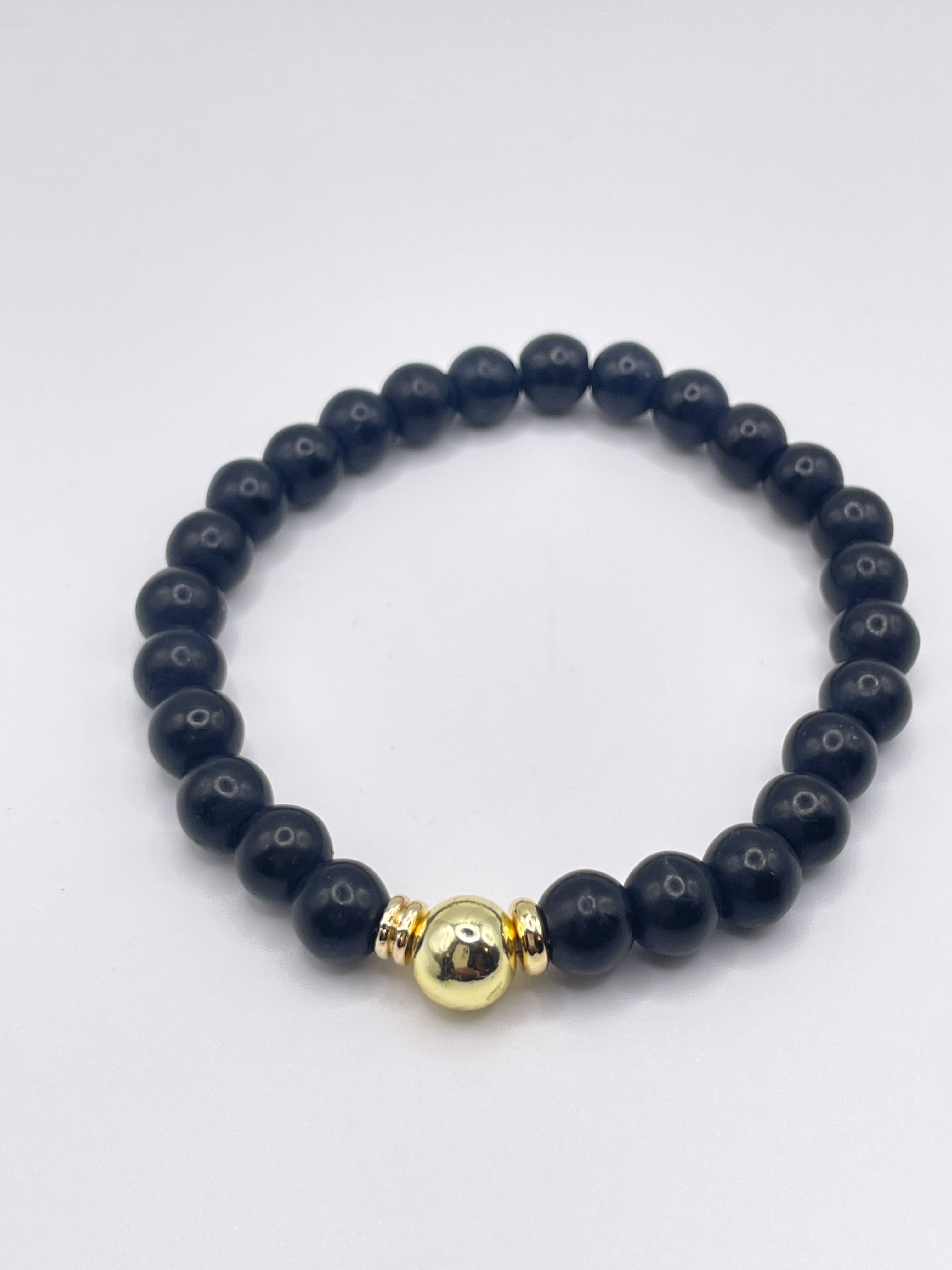 Black beaded bracelet with a gold accent on a white background