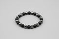 Black beaded bracelet on a gray background
