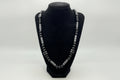 Black beaded bracelet with silver clasp on a black velvet stand against a white background