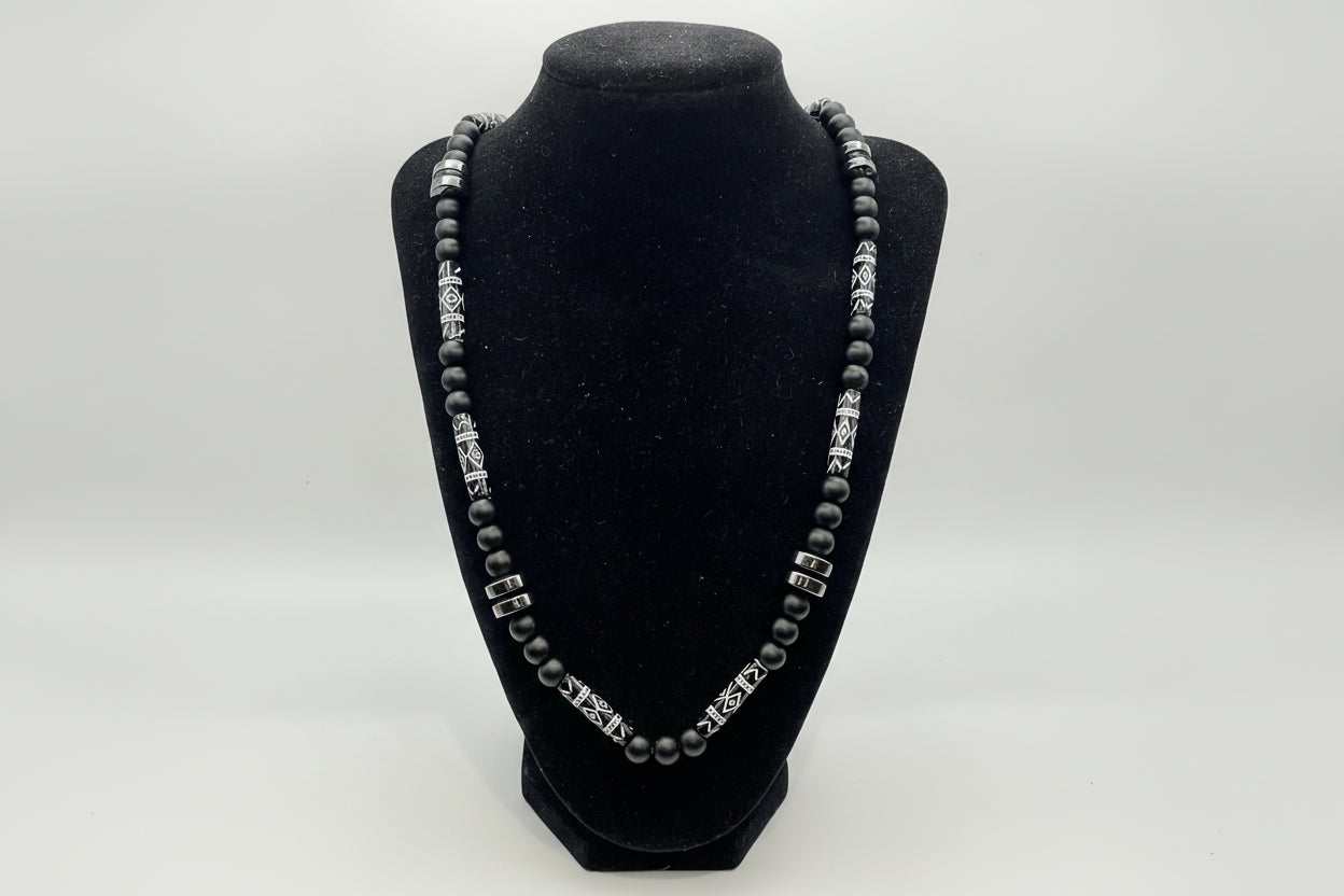 Black beaded bracelet with silver clasp on a black velvet stand against a white background