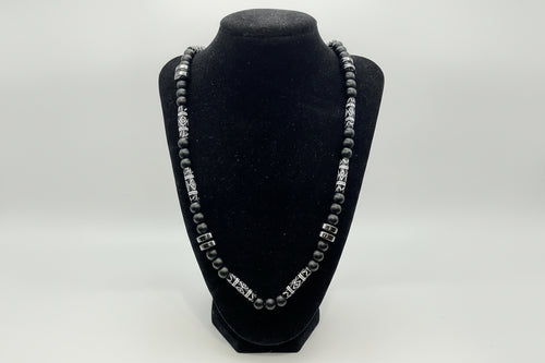 Black beaded bracelet with silver clasp on a black velvet stand against a white background