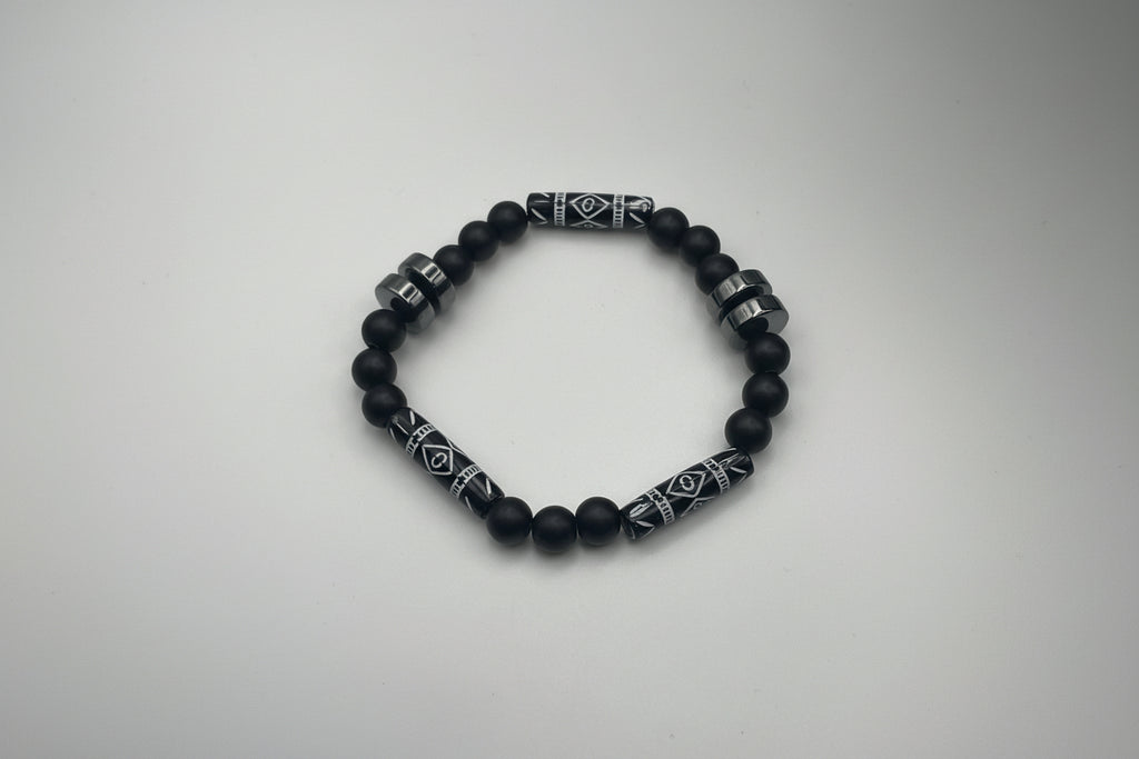 Black beaded bracelet with patterned metal accents on a white background