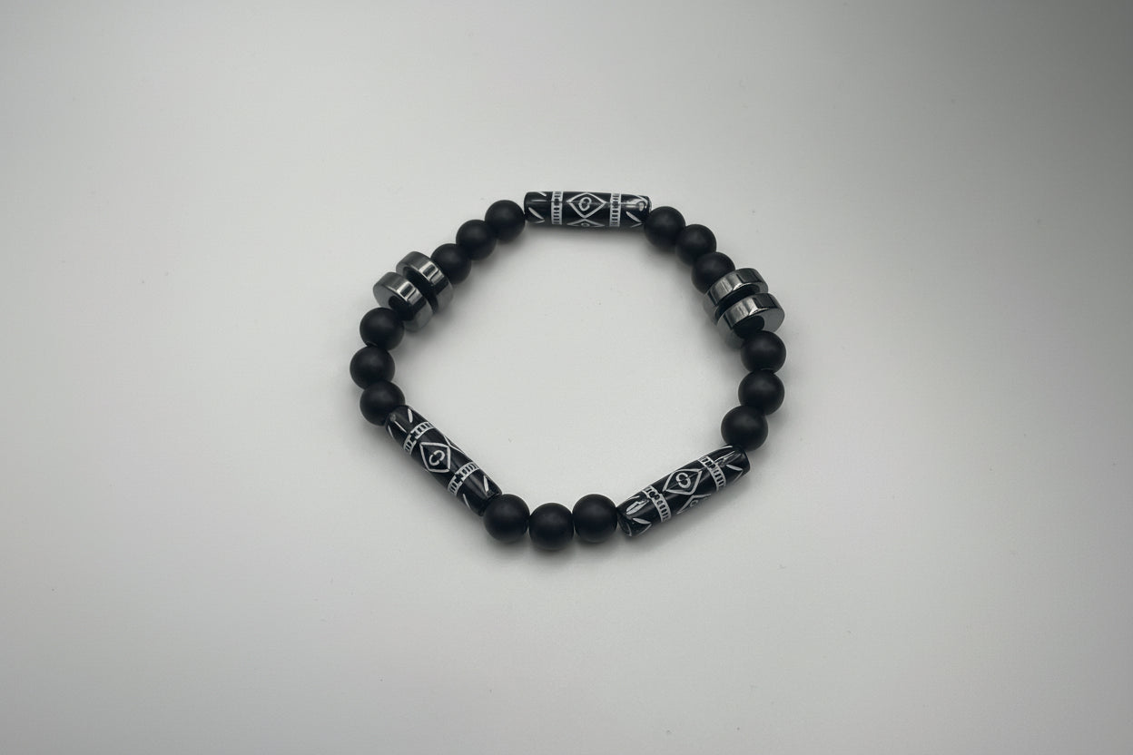 Black beaded bracelet with patterned metal accents on a white background