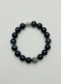 Black beaded bracelet with a silver bead on a wooden surface