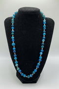 Blue beaded necklace on a black bust against a white background