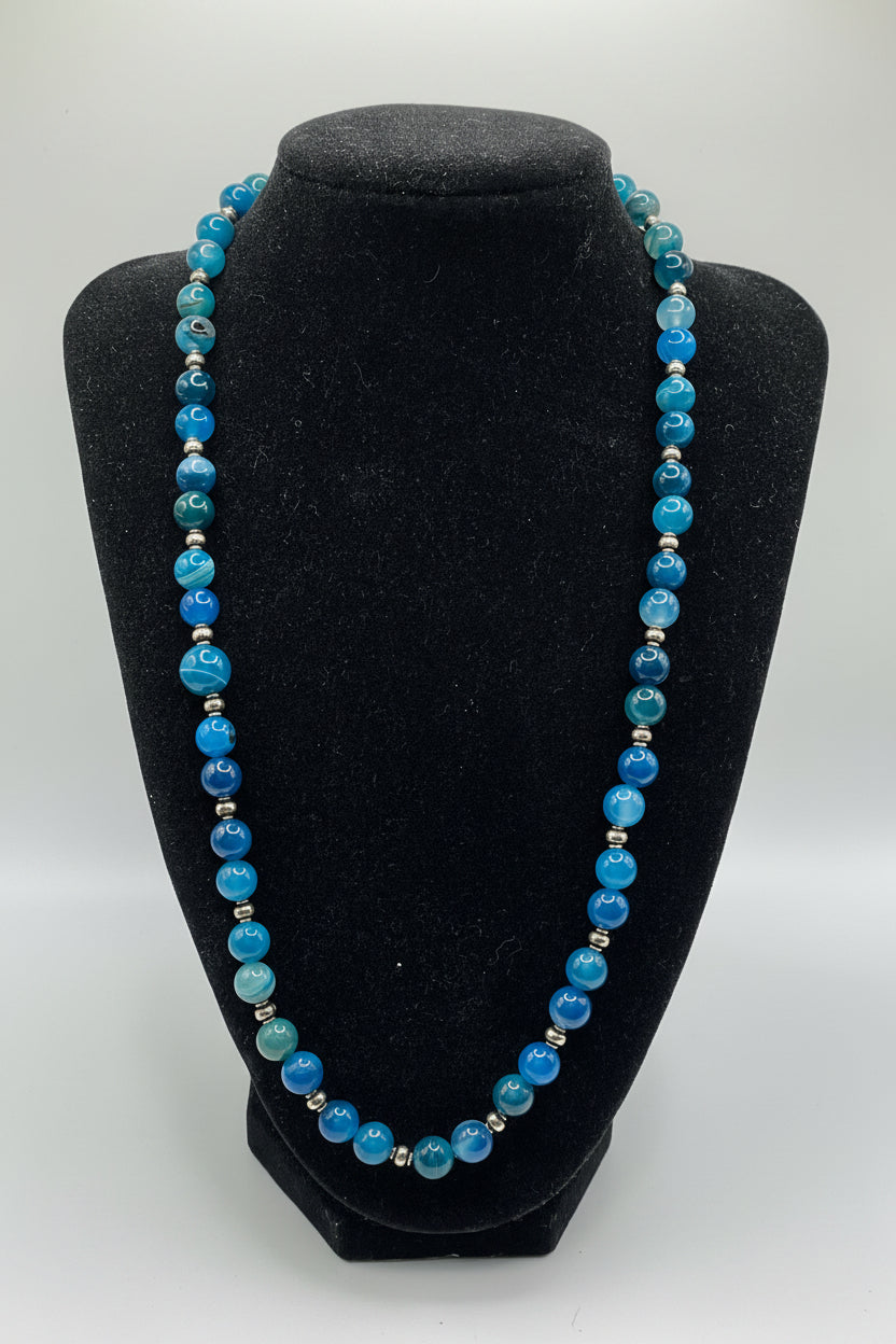 Blue beaded necklace on a black bust against a white background
