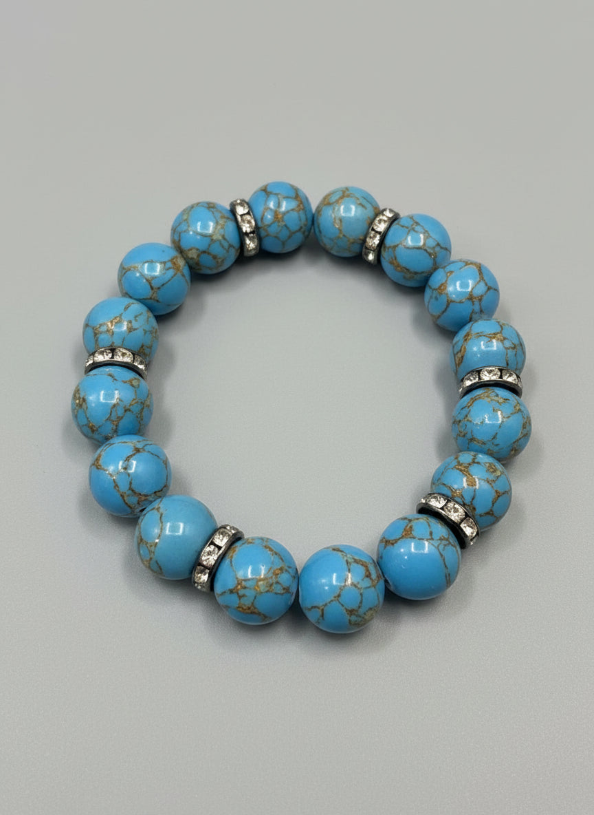 Blue beaded bracelet with gold and black accents on a wooden surface