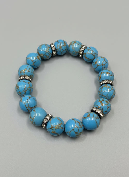 Blue beaded bracelet with gold and black accents on a wooden surface