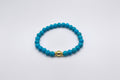 Blue beaded bracelet with a gold clasp on a white background