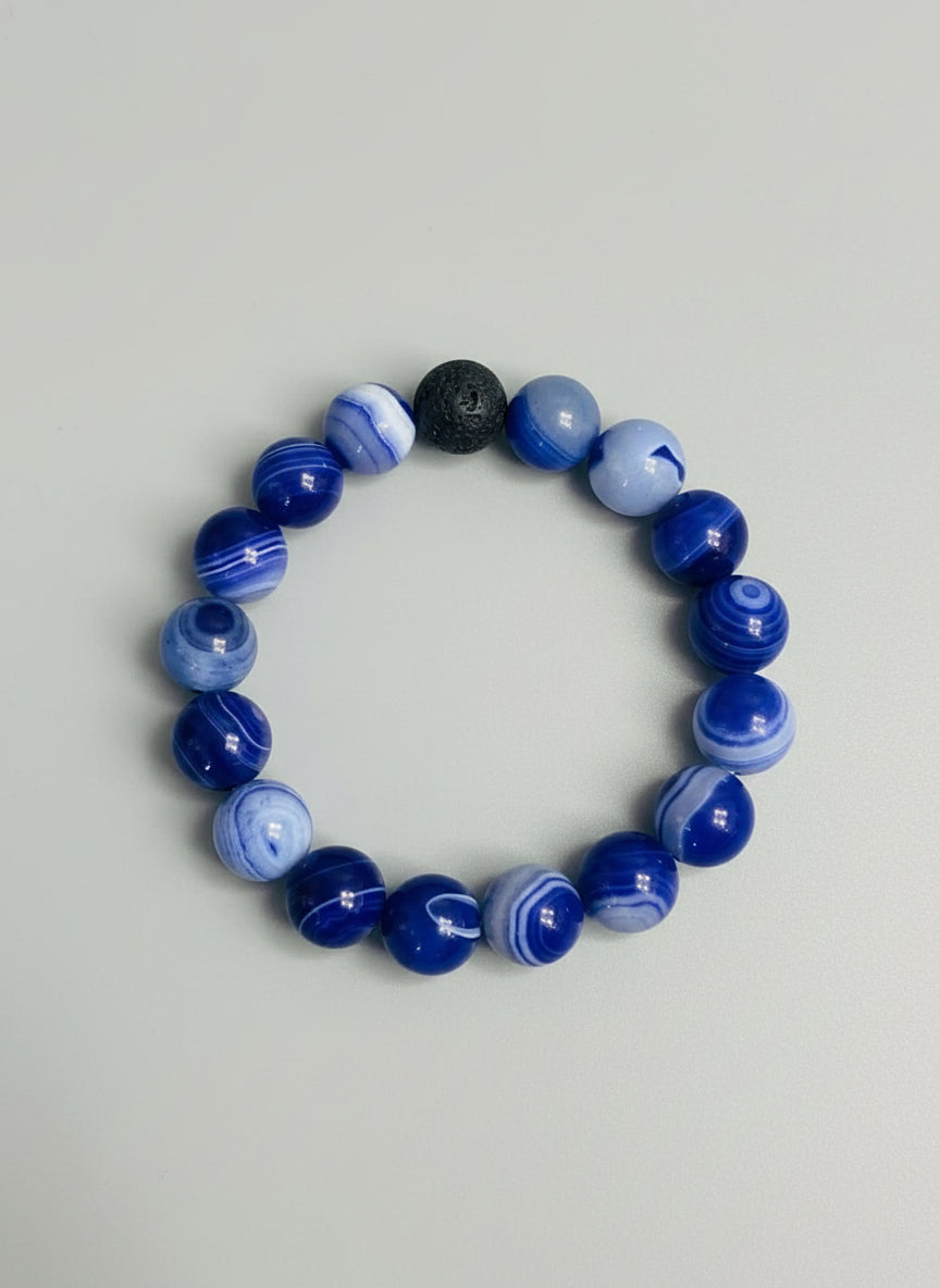 Beaded bracelet with blue, white, black and lava beads on a textured surface 