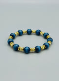 Bracelet with blue beads and gold accents on a wooden surface