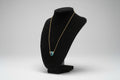 Gold chain necklace with a blue zircon gemstone on a black stand.