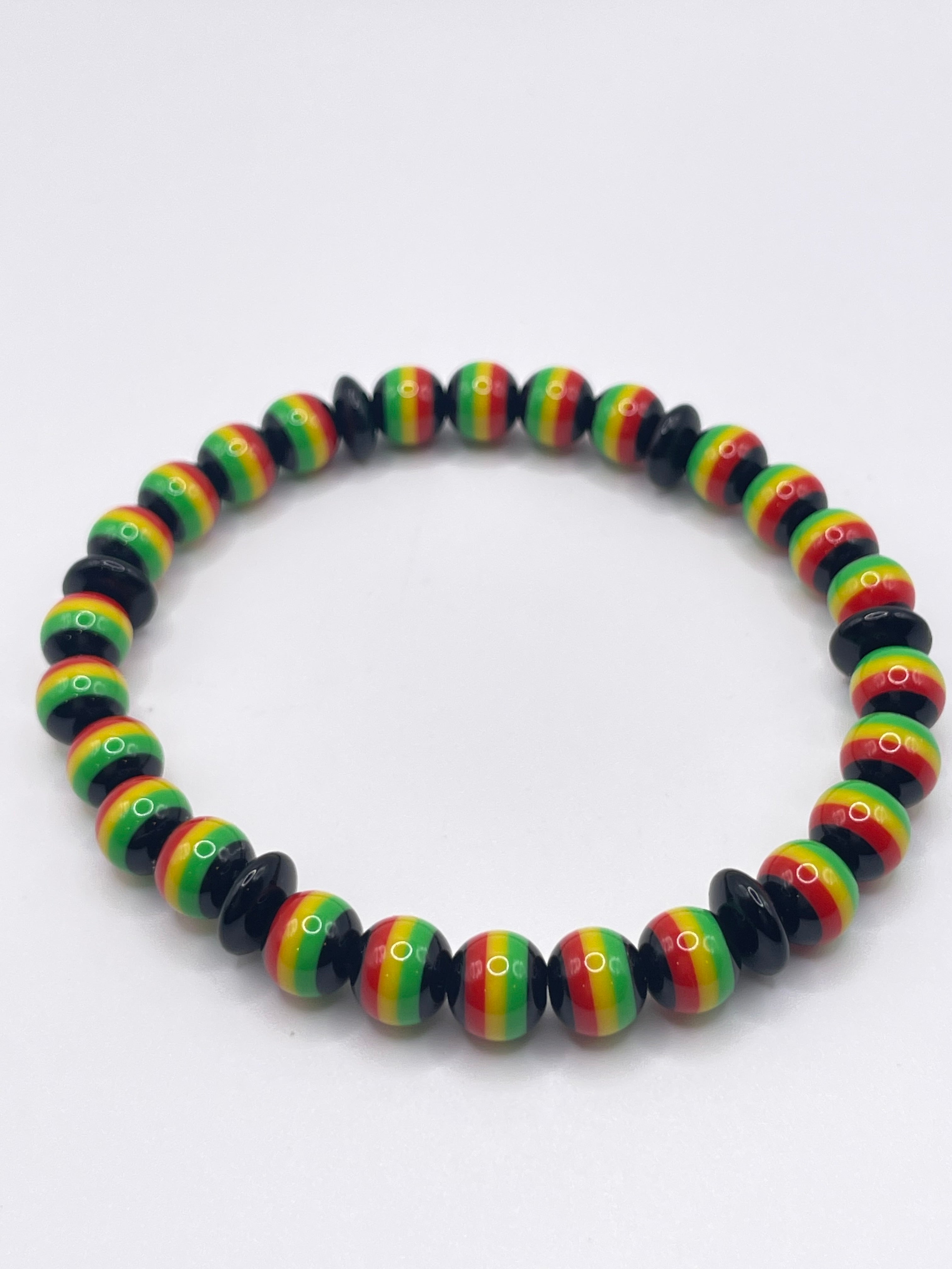 Colorful beaded bracelet with black, red, yellow, and green pattern on a white background