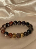 Beaded bracelet with a gold accent on a beige fabric background