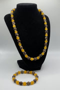 Beaded bracelet with yellow and brown beads on a black stand against a white background