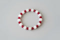 Bracelet with red and white beads on a wooden surface