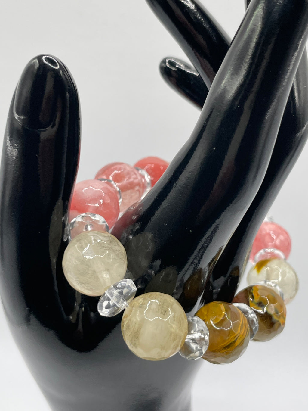 Multicolored beaded bracelet on a black stand with a white background