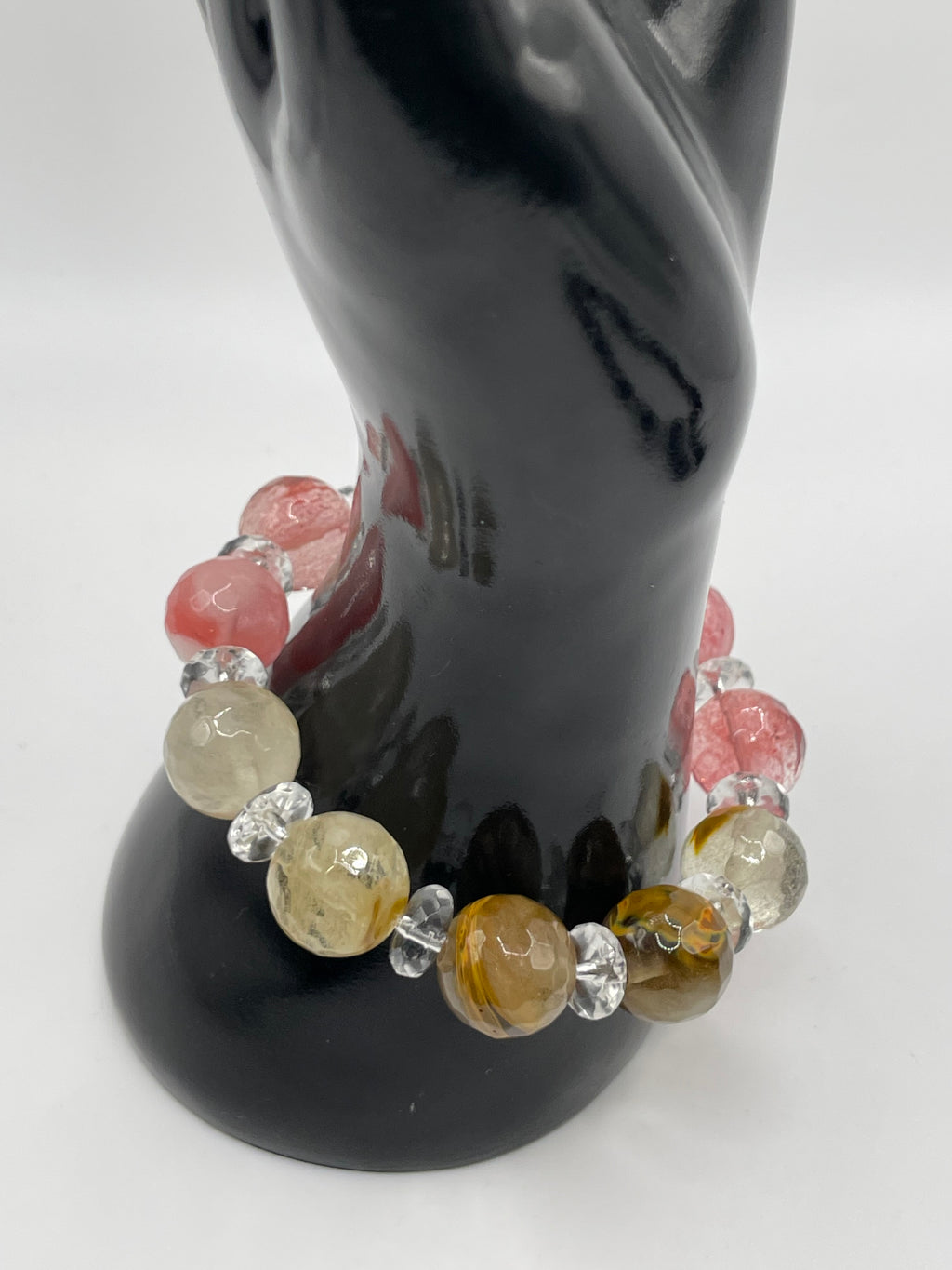 Bracelet with multicolored beads on a black hand holding a white object.