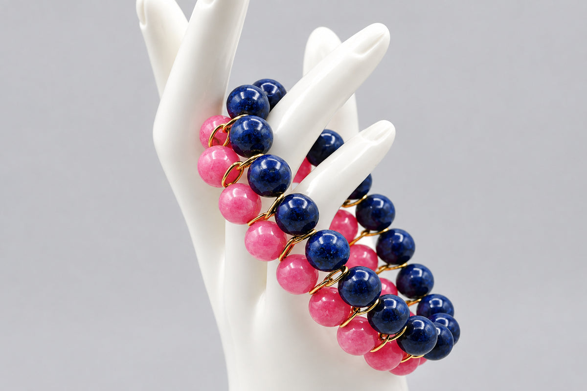 Three beaded stretch bracelets with alternating navy blue and pink beads separated by small gold spacers, displayed on a white ceramic mannequin hand against a light gray background.
