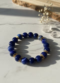 Blue beaded bracelet with gold accents on a textured gray background