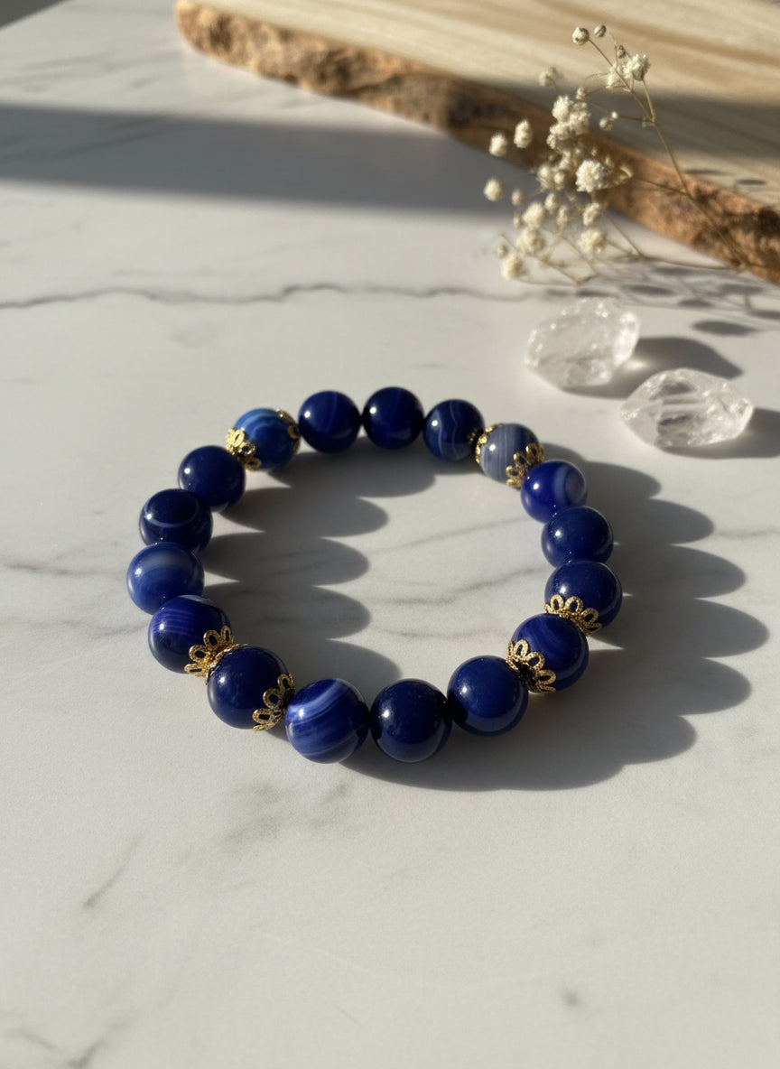 Blue beaded bracelet with gold accents on a textured gray background