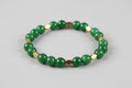 Green beaded bracelet with gold accents on a wooden surface