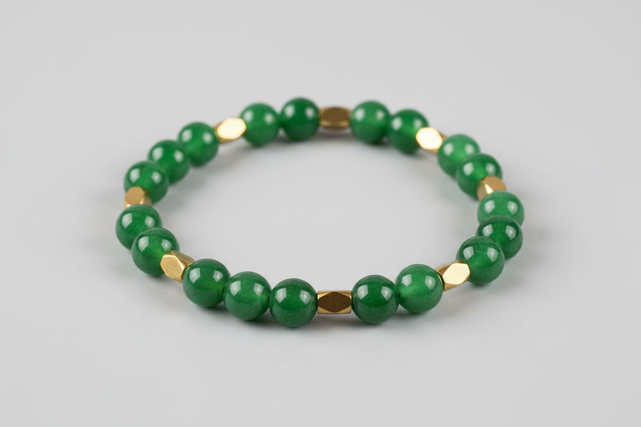 Green beaded bracelet with gold accents on a wooden surface