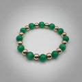 Green beaded bracelet with gold accents on a gray background