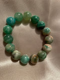 Green beaded bracelet on a beige fabric background