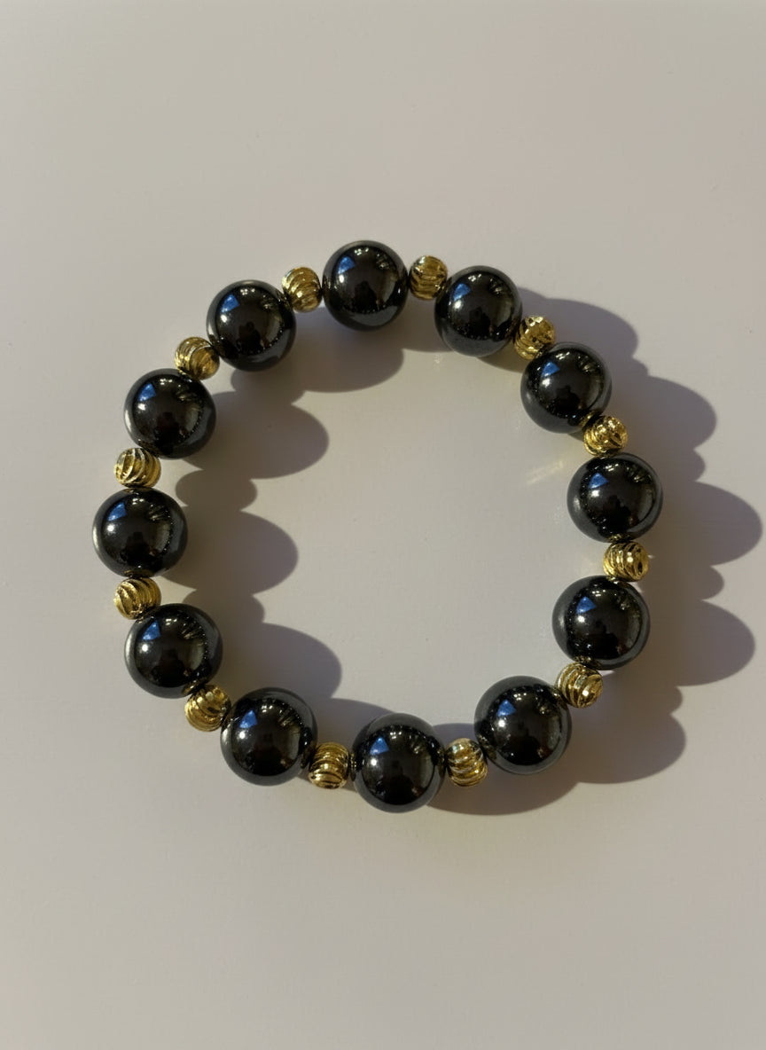 Bracelet with black beads and gold accents on a white background