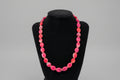 Pink beaded necklace on a black stand
