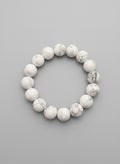 White marbled beaded bracelet on a textured black background