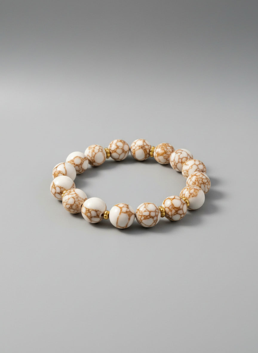 Beaded bracelet with white and gold marbled beads on a dark textured background
