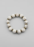 White beaded bracelet with gold accents on a dark textured surface