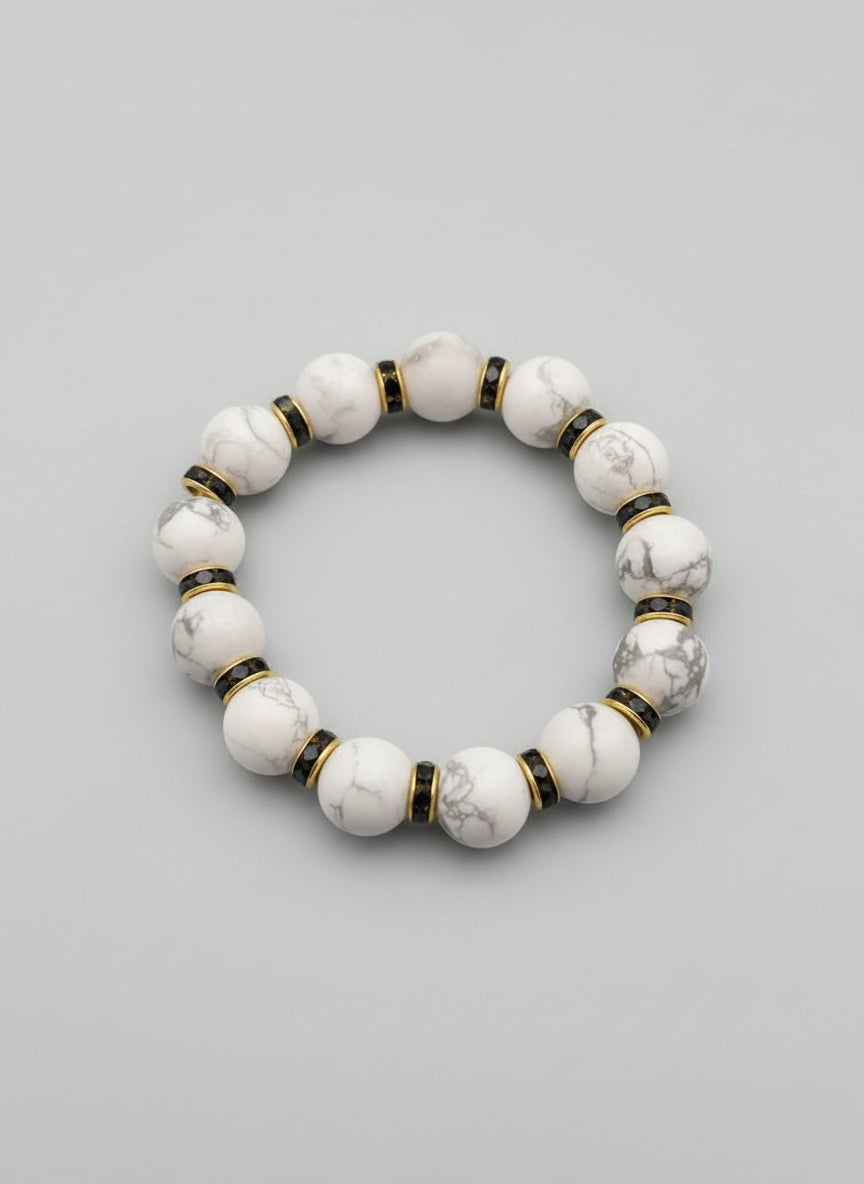 White beaded bracelet with gold accents on a dark textured surface
