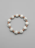 Bracelet with white beads and a tag on a dark textured surface