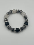 Beaded bracelet with black, gray, and white beads on a light gray background