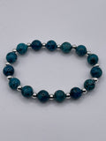 Blue beaded bracelet with silver accents on a gray background