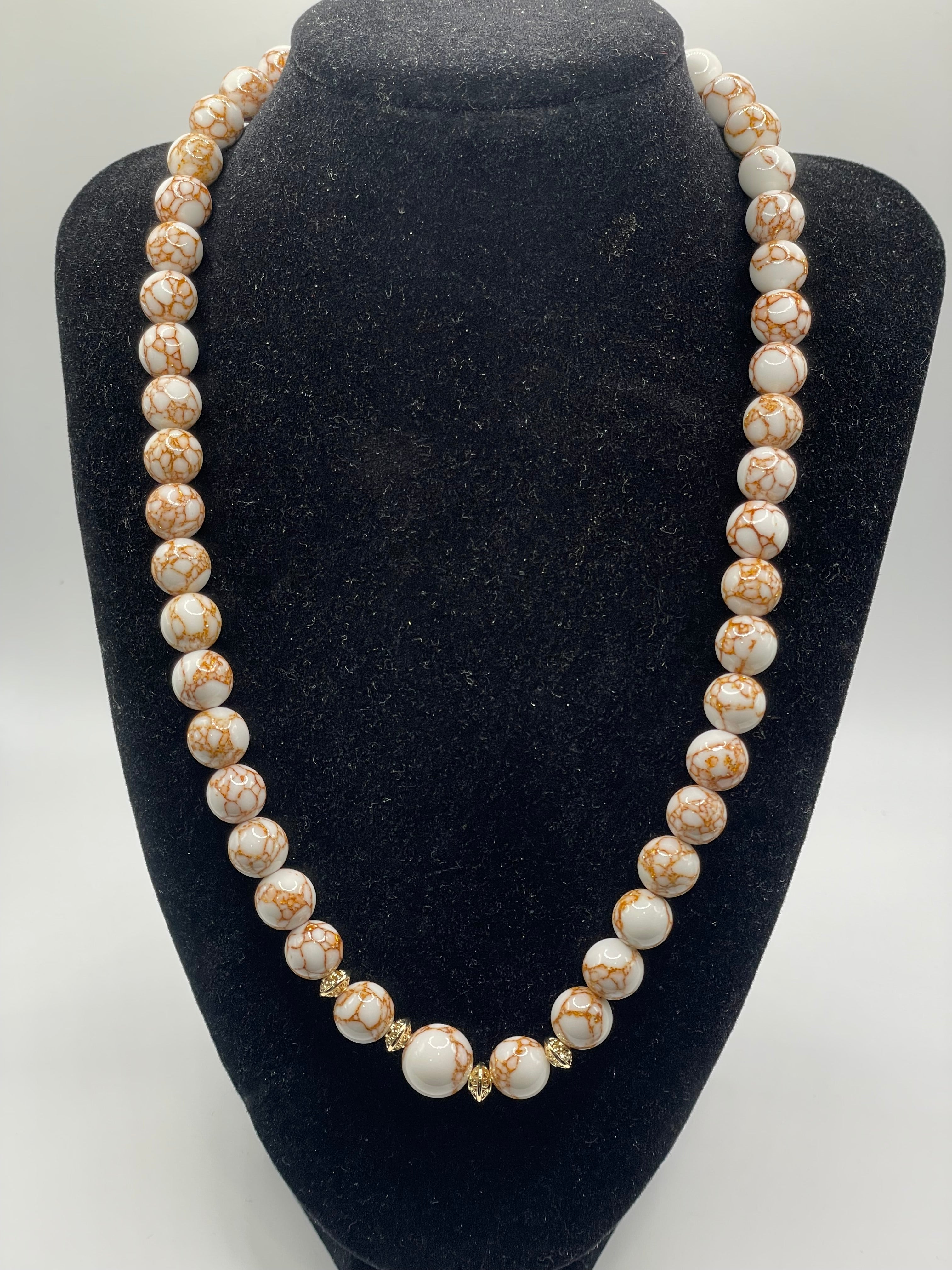 Pearl necklace on a black velvet stand with a white background