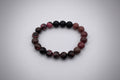 Bracelet with dark and reddish-brown beads on a white background
